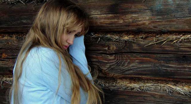 girl leaning on a wood wall